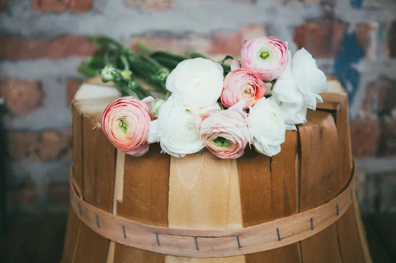 Foto de ejemplo: ranúnculos blancos y rosa pálido sobre un cesto de madera